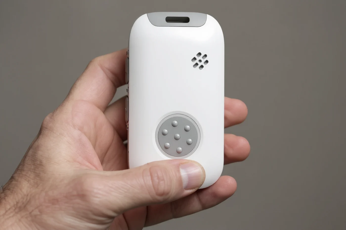 A hand holding the JAMES T9 Pro, thumb resting by the tactile SOS button